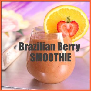 Glass of Brazilian berry smoothie garnished with a slice of orange and half a strawberry, on a soft pastel background.